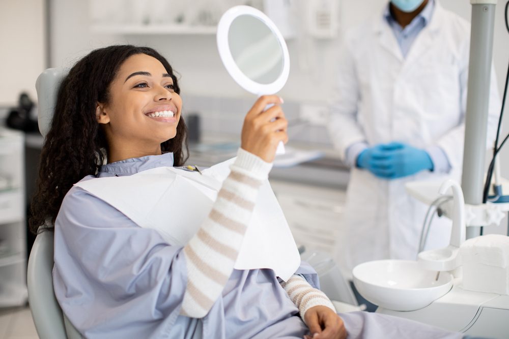 patient looking at her new smile in the mirror at the dentist